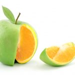 A wedge is cut out of a green apple, revealing the flesh of an orange.