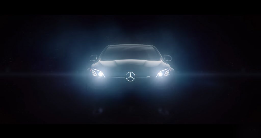 A Mercedes-Benz shines its lights in complete darkness.