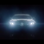 A Mercedes-Benz shines its lights in complete darkness.